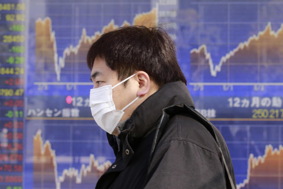 A man walks by an electronic stock board of a securities firm in Tokyo, Wednesday, Jan. 20, 2021. Asian shares were mostly higher Wednesday, ahead of Joe Biden's inauguration as president, ending President Donald Trump’s four-year term. Japan's benchmark lost early gains as worries grew about the surge in coronavirus cases. (AP Photo/Koji Sasahara)