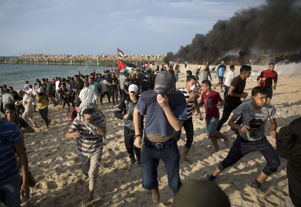 Palestinian protesters run for cover from teargas fired by Israeli troops during a protest on the beach at the border with Israel near Beit Lahiya, northern Gaza Strip, Monday, Oct. 15, 2018.(AP Photo/Khalil Hamra)