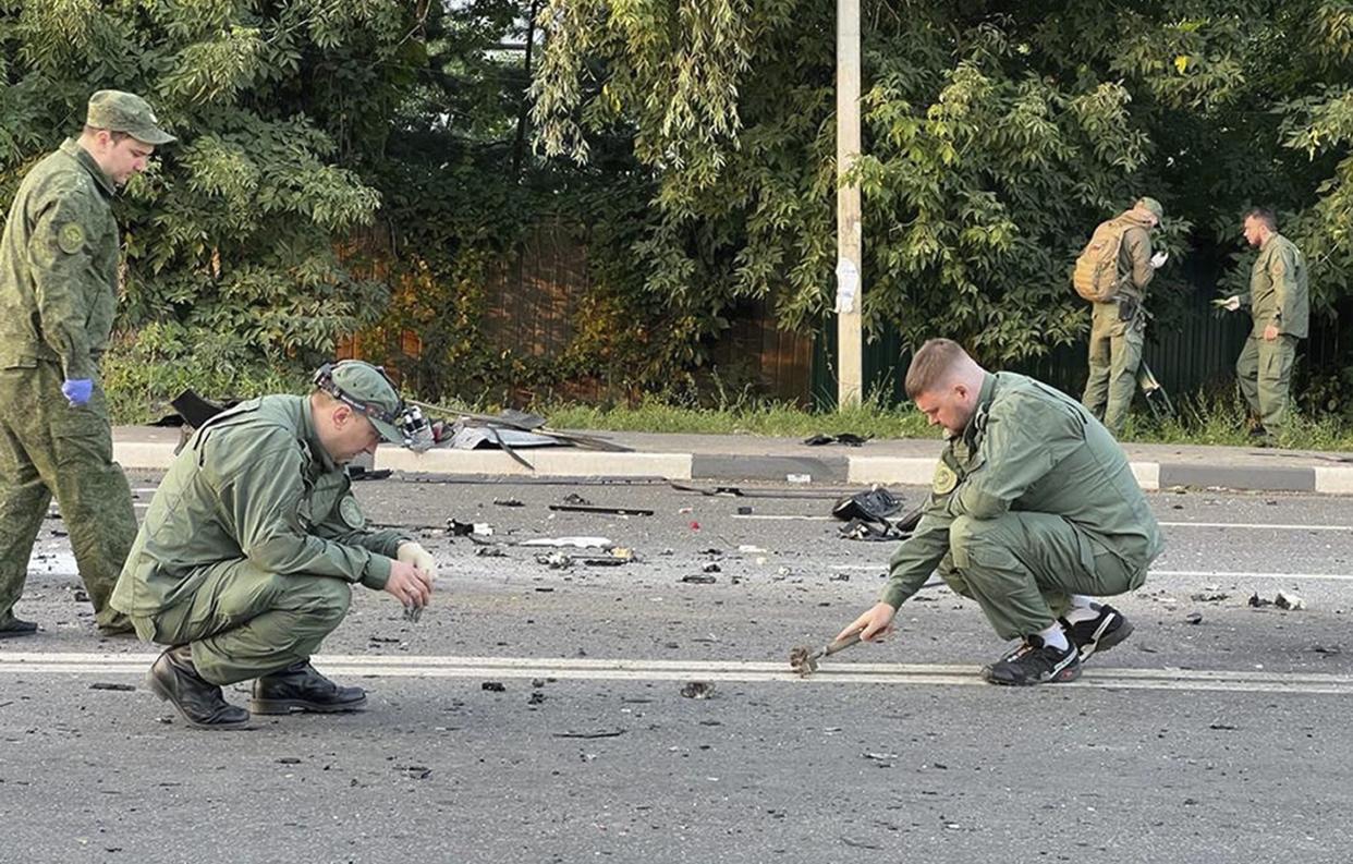 In this handout photo taken from video released by Investigative Committee of Russia on Sunday, Aug. 21, 2022, investigators work on the site of explosion of a car driven by Daria Dugina outside Moscow. 