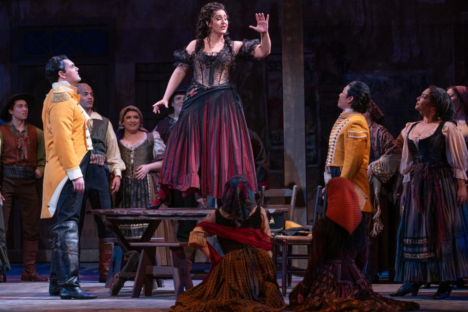 Chelsea Laggan enchants a crowd, including David Weigel, left, as Zuniga, in a scene from the Sarasota Opera production of “Carmen.”