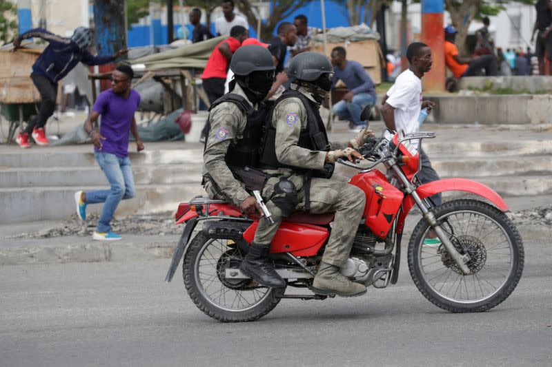 Protesters and masked men in Haitian National Police uniforms run away during a shooting in Champ de Mars, Port-au-Prince