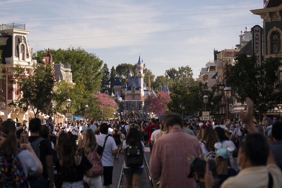 Guests walk along the Main Street USA at Disneyland in Anaheim, Calif., Friday, April 30, 2021. The iconic theme park in Southern California that was closed under the state's strict virus rules swung open its gates Friday and some visitors came in cheering and screaming with happiness. (AP Photo/Jae C. Hong)