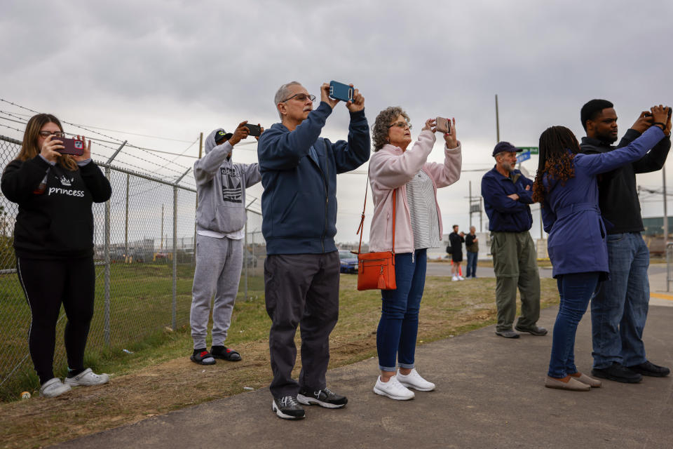 People look and take photos as workers start to remove a section of the collapsed Francis Scott Key Bridge, Saturday, March 30, 2024, in Baltimore. (AP Photo/Julia Nikhinson)