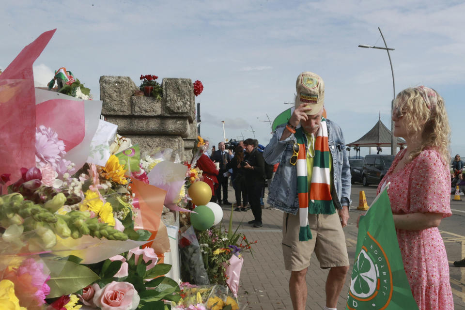 personas miran ofrendas colocadas fuera de la antigua casa de Sinéad O'Connor antes del funeral de la cantante en Bray en el condado de Wicklow, Irlanda el martes 8 de agosto de 2023. (Liam McBurneyPA vía AP)