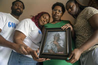 Janet Hartford, center, the wife of Anthony Hartford, 53, whose body was found among the dead on the Seacor Power, holds a photo of her husband while standing with her daughter, Antranae, 24, right, son, Thelonious Dukes, 38, far left, and daughter-in-law, Chantrice, at their home in New Orleans on Saturday, April 17, 2021. Divers returned Saturday to the murky, roiling waters of the Gulf of Mexico in search of lost crew members aboard a capsized lift boat off Louisiana, the Coast Guard said. (Chris Granger/The Times-Picayune/The New Orleans Advocate via AP)