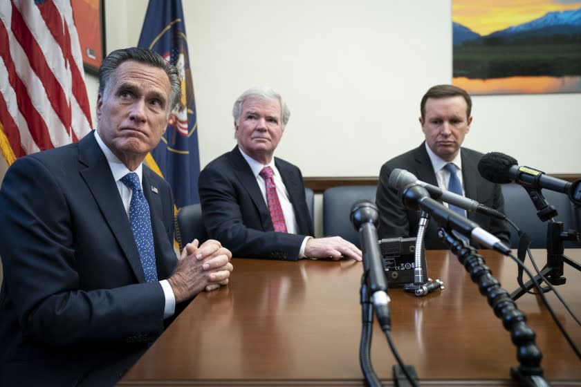 NCAA President Mark Emmert is flanked by Sens. Mitt Romney, left, and Chris Murphy during a news conference.