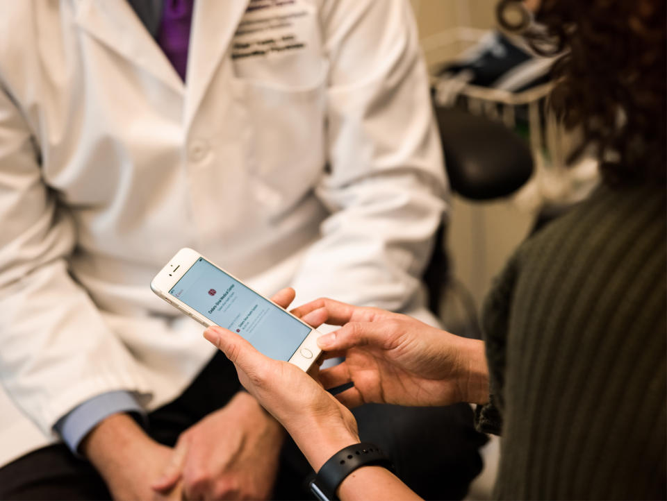 A woman meeting with a doctor looking at health records on her iPhone