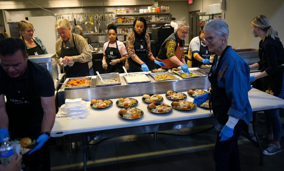 Volunteers serve up plates of food Wednesday, Nov. 23, 2022, during a Thanksgiving meal at the Homeless Alliance.