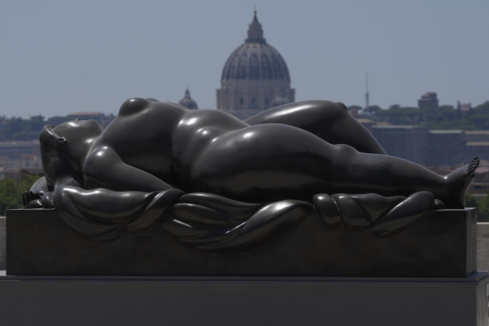 La escultura "Venus dormida", de Fernando Botero, instalada en el mirador de Pincio, en Roma, el 19 de julio de 2024, parece estar en frente de la Basílica de San Pedro del Vaticano. Las calles y plazas de Roma son un vibrante lienzo para las exuberantes esculturas de Botero, convirtiendo la ciudad en un museo al aire libre para las voluminosas formas creadas por el colombiano. (AP Foto/Gregorio Borgia)