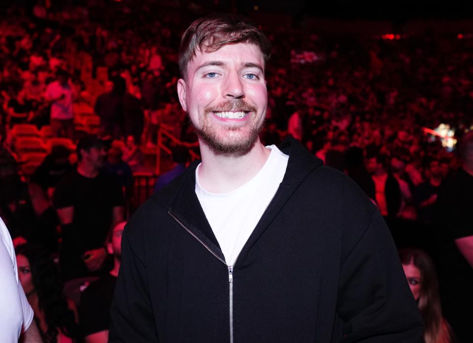 MrBeast smiling whilst wearing a white t-shirt and black hoodie