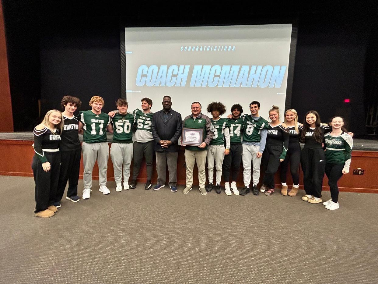 Grafton football captains and cheerleaders surround coach Chris McMahon and New England Patriots legend Andre Tippett after the Patriots honored McMahon as their Coach of the Week.