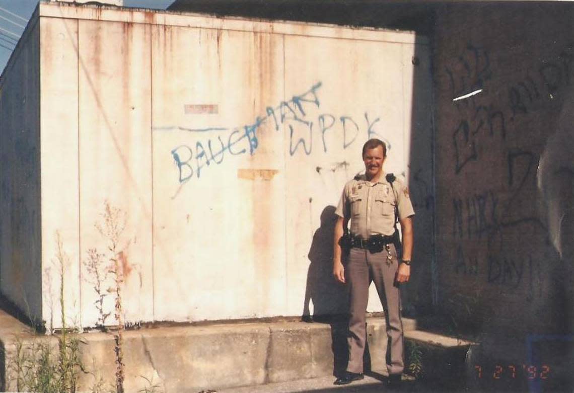 A photo of Wichita Police Officer Bob Bachman, in a photo from his early days on the force, stands next to graffiti that indicates a death threat towards him. Bachman was a long-time member of the SWAT team and has been involved in two officer-involved shootings.
