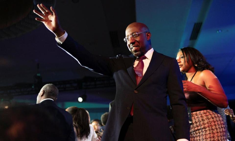 Raphael Warnock in a suit gesturing with one hand.