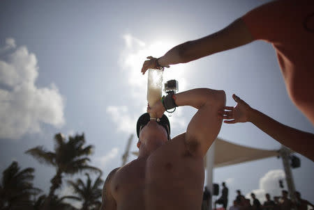 A spring breaker drinks from a bottle during games held at a beach in Cancun March 7, 2015. REUTERS/Victor Ruiz Garcia