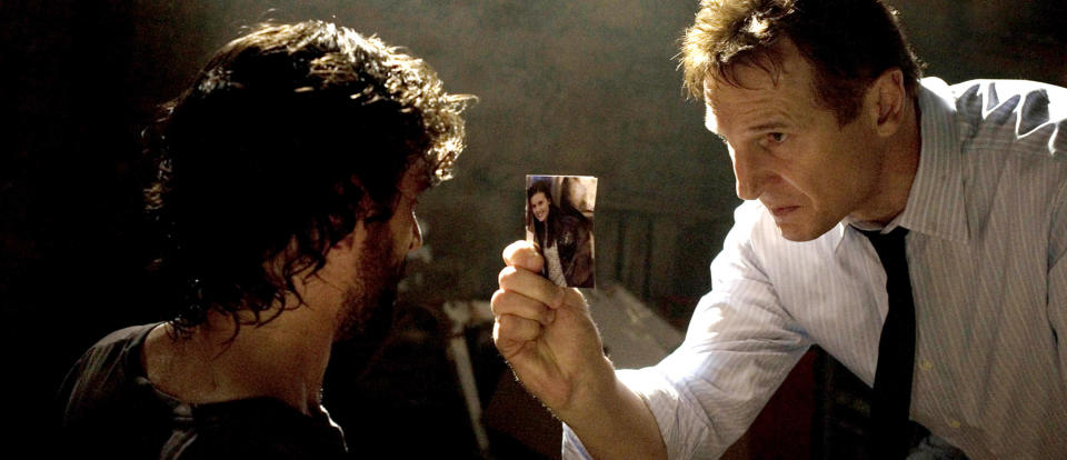 Liam Neeson holding up a photo