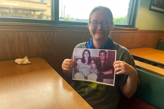 <p>Mindy Montford / POLARIS</p> Holly holds a photo of herself and her parents after she is visited by law enforcement in June of 2022