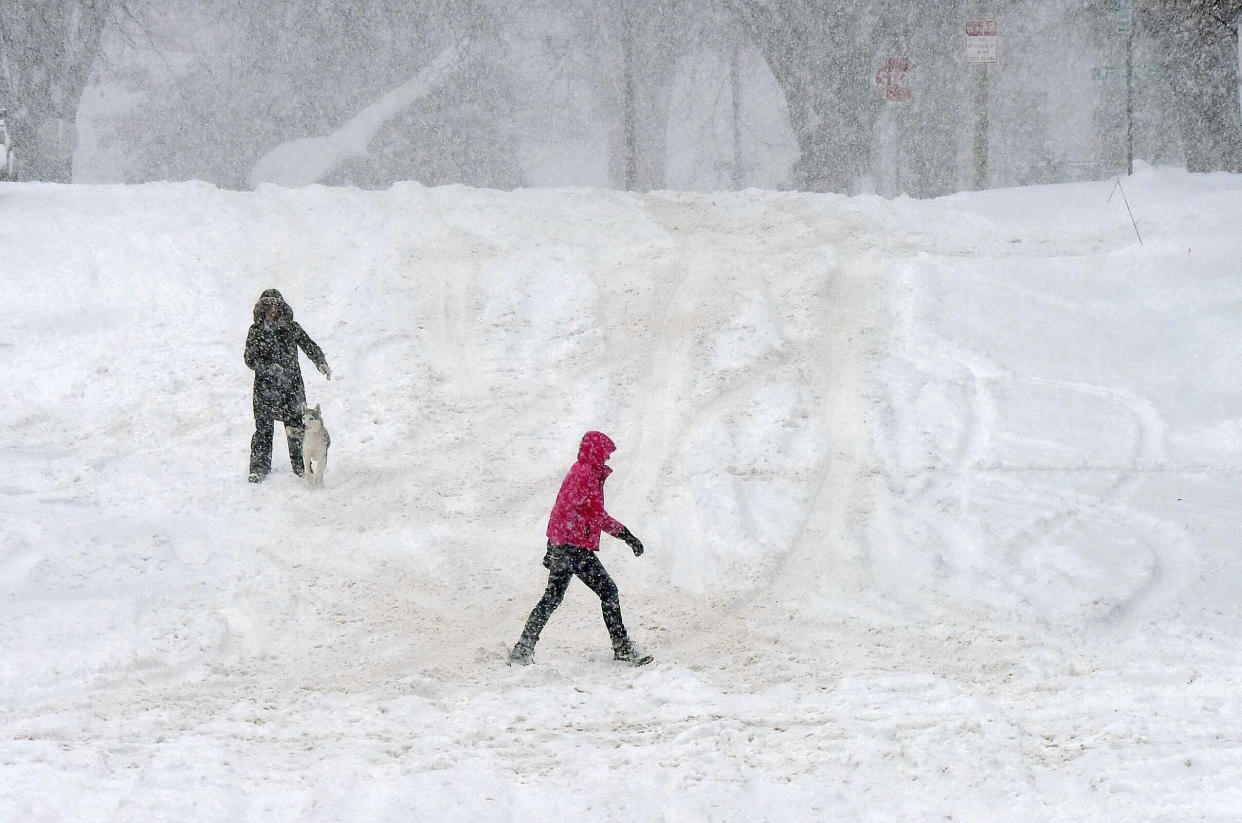 With most city streets in Bismarck, N.D., impassable due to accumulating snow, walking proves to be the best way to get around on Wednesday, Dec. 14, 2022, as snow continued to fall in the area. This view shows Thayer Avenue near Mandan Street in Bismarck. (Tom Stromme/The Bismarck Tribune via AP)