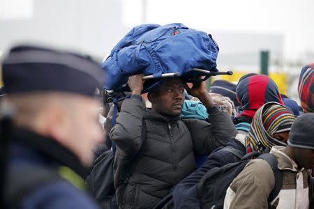 French police stand near as migrants with their belongings queue near barriers at the start of their evacuation and transfer to reception centers in France, and the dismantlement of the camp called the "Jungle" in Calais, France, October 24, 2016. REUTERS/Pascal Rossignol