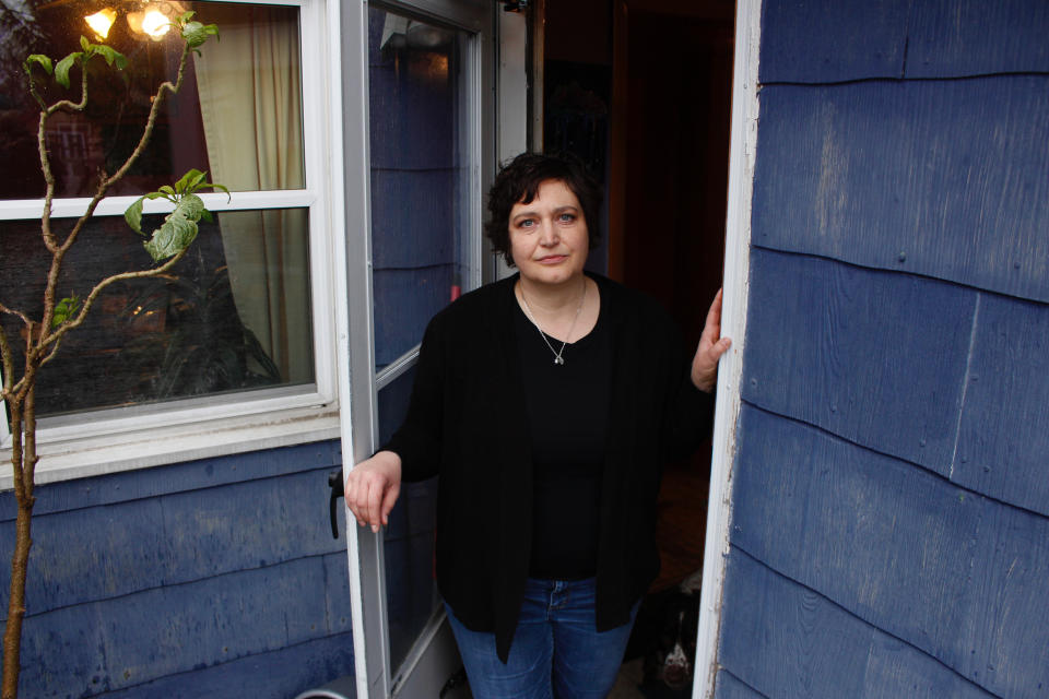 In this April 29, 2020 photo, Julie Hitchcock stands in her back doorway in Milwaukee. Hitchcock, 49, said she worries about getting sick or unknowingly infecting someone else, anxiety that's heightened because she was on a ventilator for two weeks last fall after developing pneumonia. As the coronavirus pandemic upends lives across the nation, a new poll conducted by NORC at the University of Chicago for the Data Foundation found that most Americans reported feeling nervous, depressed, lonely or hopeless in the last week. (AP Photo/Carrie Antlfinger)