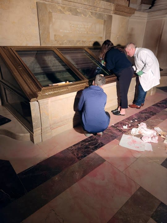 National Archives employees clean pink powder on the casement of the U.S. Constitution inside the National Archives Rotunda in Washington, Feb. 14, 2024. The National Archives building and galleries were evacuated after two protesters dumped powder on the protective casing around the U.S. Constitution. (William J. Bosanko/National Archives via AP)