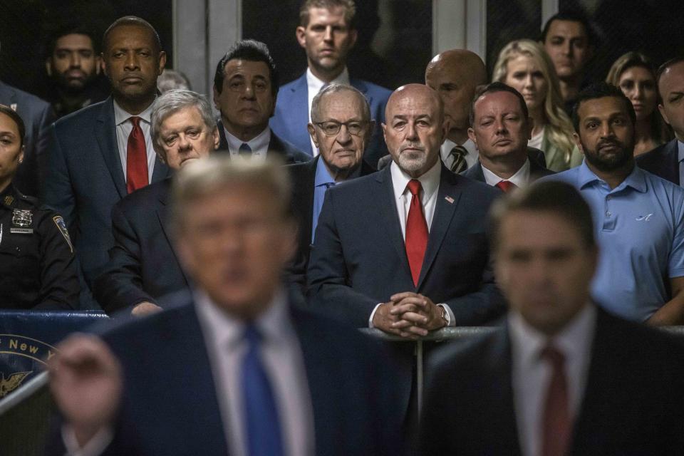 Attorney Alan Dershowitz, background center left in blue shirt, listens to remarks by former President Donald Trump during his ongoing trial at Manhattan Criminal Court in New York, Monday, May 20, 2024. (Dave Sanders/The New York Times via AP, Pool),