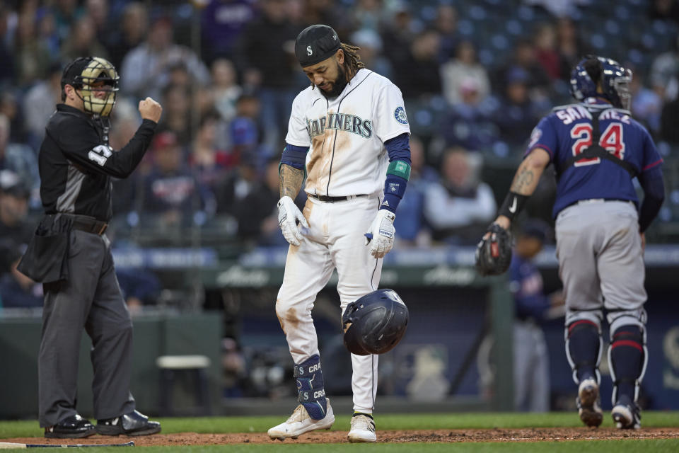 Seattle Mariners' J.P. Crawford drops his helmet after striking out to end the fifth inning against the Minnesota Twins during a baseball game, Monday, June 13, 2022, in Seattle. Umpire DJ Reyburn, left, makes the call and Twins catcher Gary Sanchez (24) runs to the dugout. (AP Photo/John Froschauer)