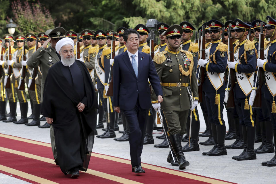 Japanese Prime Minister Shinzo Abe, center, reviews an honor guard as he is welcomed by Iranian President Hassan Rouhani, left, in an official arrival ceremony at the Saadabad Palace in Tehran, Iran, Wednesday, June 12, 2019. The Japanese leader is in Tehran on an mission to calm tensions between the U.S. and Iran. (AP Photo/Ebrahim Noroozi)