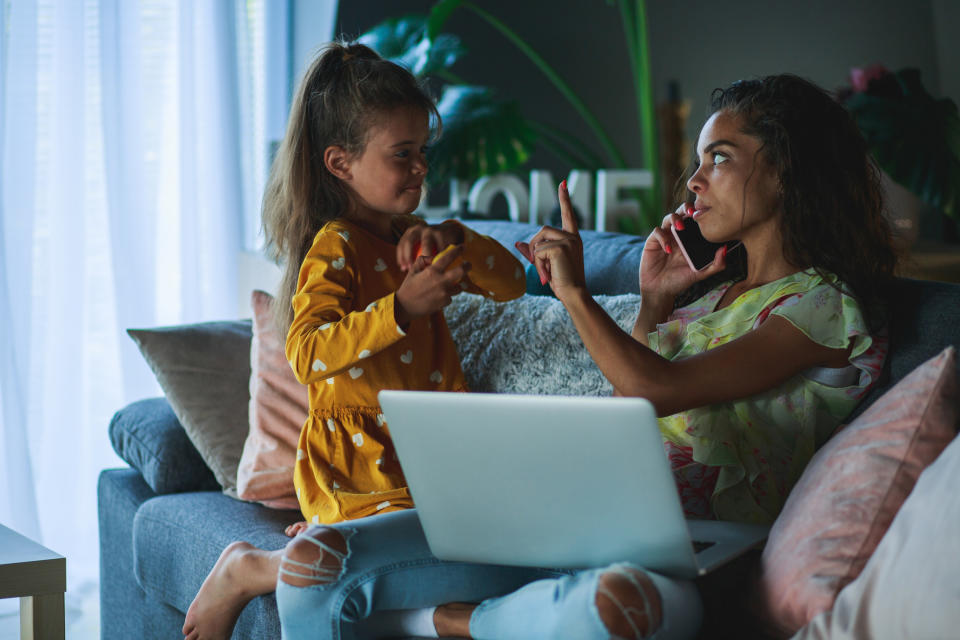 a mother holding a finger up to her daughter to wait while she's on a business call