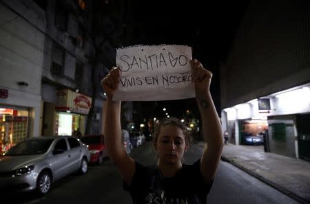 A woman holds up a sign refering to Santiago Maldonado, a protester who went missing since security forces clashed with indigenous activists in Patagonia on August 1, 2017, during a demonstration outside a judicial morgue in Buenos Aires, Argentina October 20, 2017. The sign reads "Santiago, you live among us". REUTERS/Marcos Brindicci