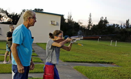 Viera Rybak, 12, shoots as instructor Steve Norris looks on during a clay target youth group shooting meeting in Sunrise, Florida, U.S. February 26, 2018. Picture taken February 26, 2018. REUTERS/Joe Skipper