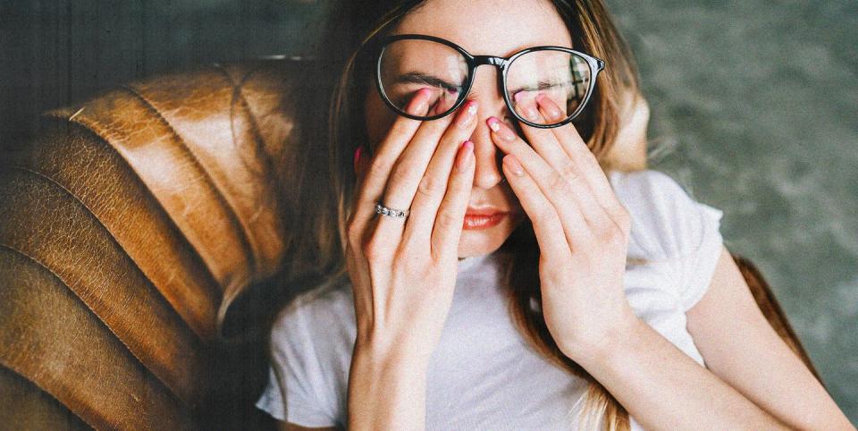 young woman looking stressed and slumped in a leather chair covering her eyes