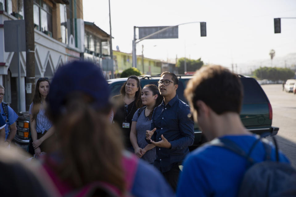 In this Oct. 26, 2019, photo, University of California San Diego medical student Phil Canete, center, addresses a group of volunteer health practitioners from Mexico and the United States before heading out to set up clinics at shelters for migrants in Tijuana, Mexico. A burgeoning grassroots movement of health professionals and medical students from both sides of the U.S.-Mexico border is quietly battling on the front lines to keep asylum seekers healthy and safe. It is a daunting task taken on by volunteers trying to desperately tend to a need left largely unmet by the governments of both countries. (AP Photo/Gregory Bull)
