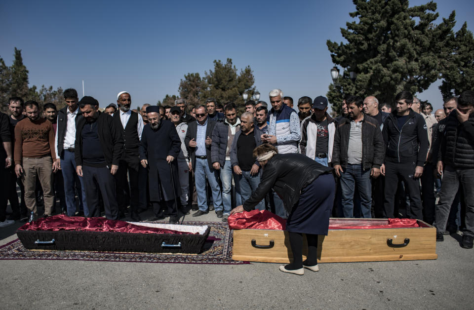 People attend the funeral prayers for three members of an Azerbaijani Turkish family, Royal Shahnazarov, his wife Zuleyxa Shahnazarova and their one-year-old baby girl Madina, who were killed by overnight shelling by Armenian forces in Ganja, Azerbaijan, Saturday, Oct. 17, 2020. Azerbaijan has accused Armenia of striking its second-largest city with a ballistic missile that killed at least 13 civilians and wounded 50 others in a new escalation of their conflict over Nagorno-Karabakh. (Can Erok/DHA via AP)