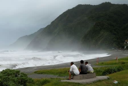 Men watch waves crash at the coast as Typhoon Nepartak approaches in Yilan, Taiwan July 7, 2016. REUTERS/Tyrone Siu