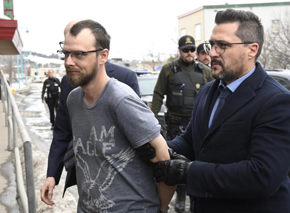 Steeve Gagnon is escorted by police into court in Amqui, Quebec, Tuesday, March 14, 2023. The 38-year-old man is facing two charges of dangerous driving causing death after after a pickup truck rammed into pedestrians. (Jacques Boissinot/The Canadian Press via AP)