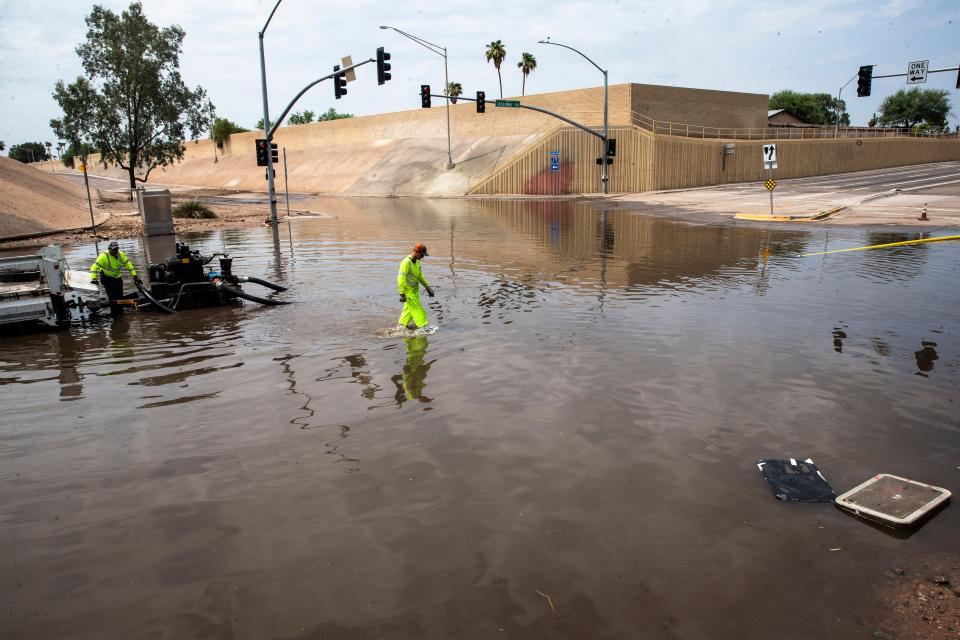 Arizona Department of Transportation workers, from left, Glenn Proudfoot and Ty Freeman pump water to clear the flooding caused by heavy monsoon rains along Greenway Road and Interstate 17 in Phoenix, Aug. 17, 2021. Benjamin Chambers/The Republic