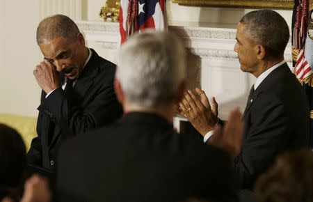 Attorney General Eric Holder wipes tears as he is applauded by President Barack Obama during Holder's statement about his resignation in the White House State Dining Room at the White House, September 25, 2014. REUTERS/Gary Cameron