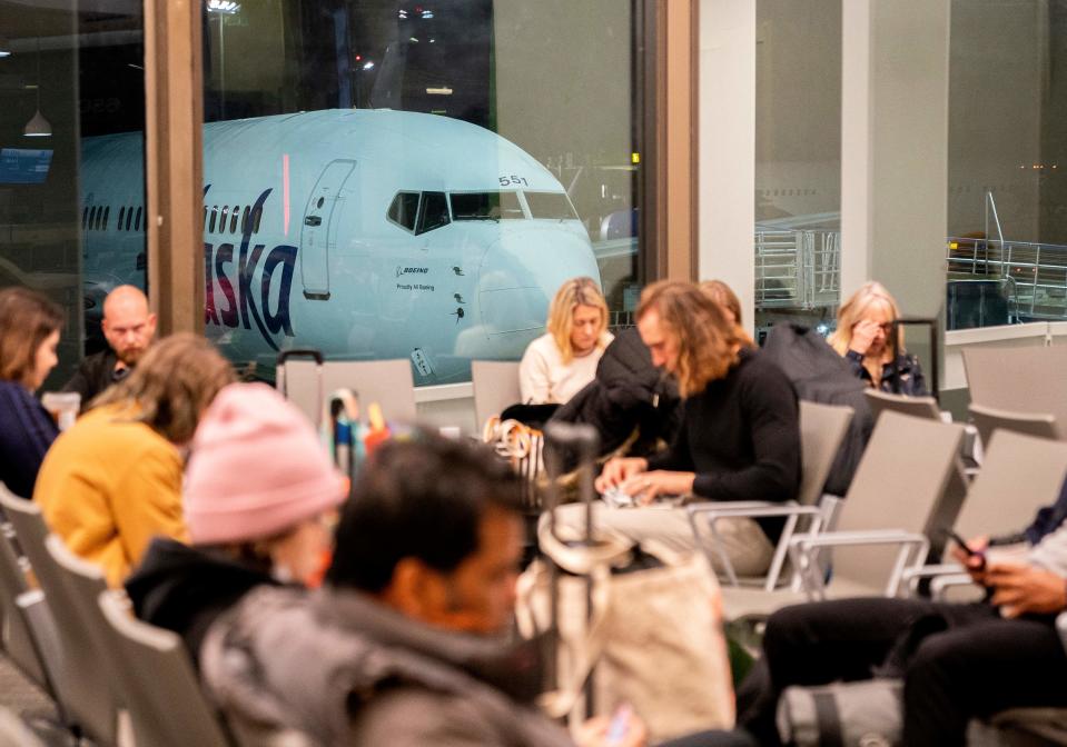 Travelers wait in the terminal as an Alaska Airlines plane sits at a gate at Los Angeles International Airport in Los Angeles, on January 11, 2023. - The US Federal Aviation Authority ordered a temporary halt to all domestic flight departures Wednesday, after a major system outage that disrupted air traffic across the country. Airlines and airports were left scrambling with news of the nationwide pause, as the White House said there was no immediate evidence of a cyberattack. (Photo by Stefani Reynolds / AFP) (Photo by STEFANI REYNOLDS/AFP via Getty Images)