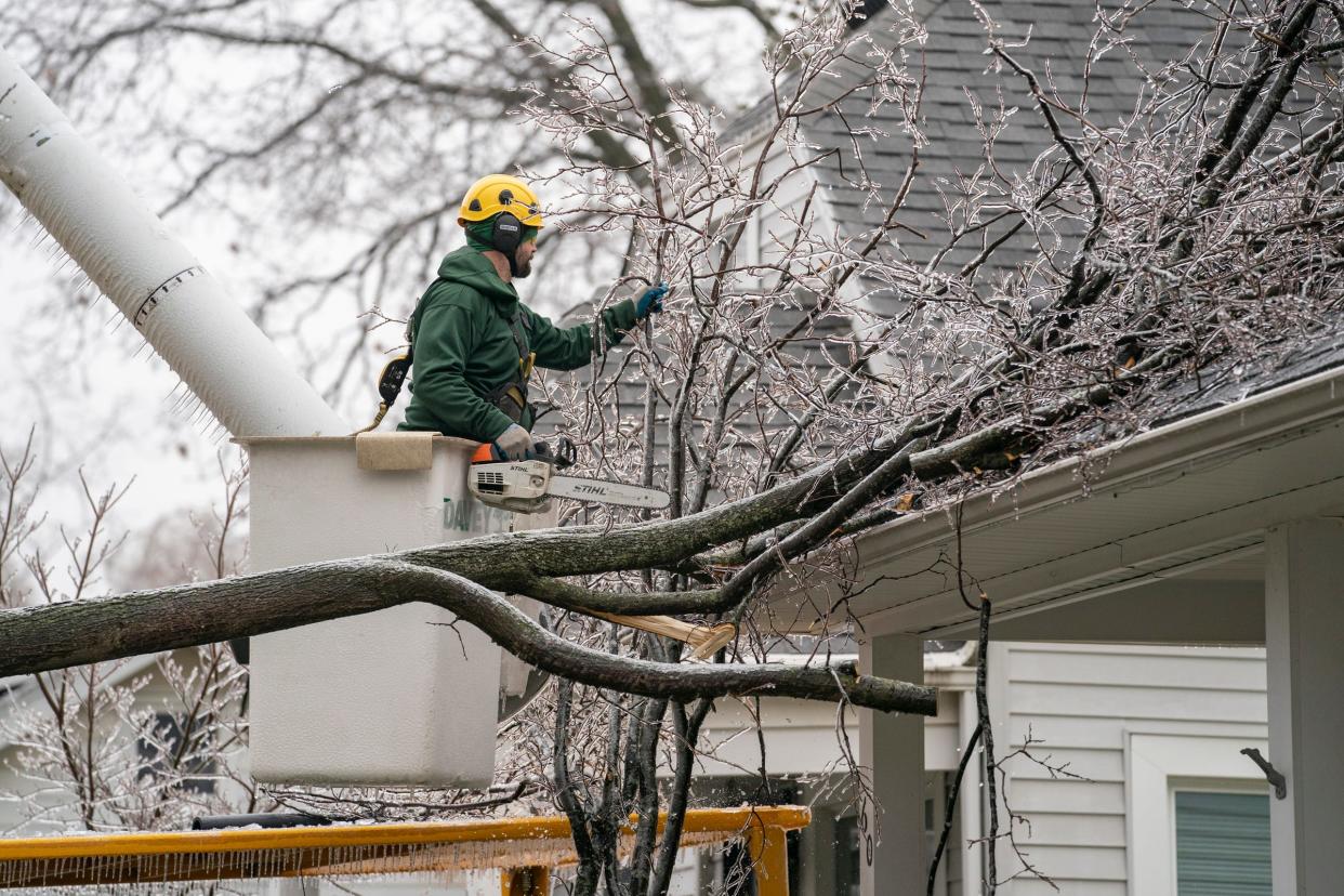 A crew from Davey Tree out of Auburn Hills cut a large tree branch back from a residential home and sidewalk on Woodward Heights in Pleasant Ridge as ice covers the Metro Detroit area causing widespread power outages on Thursday, Feb. 23, 2023.