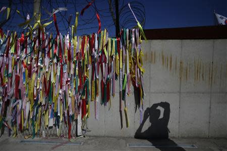 A visitor takes photographs of military fences decorated with ribbons, on which people have written their hopes for peace and reunification of the divided Korean peninsula, at the Imjingak pavilion near the demilitarized zone which separates the two Koreas, in Paju, north of Seoul October 16, 2013. REUTERS/Kim Hong-Ji