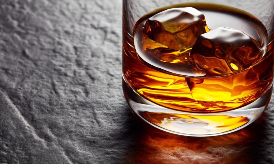 Glass of whiskey with ice cubes on a black stone table