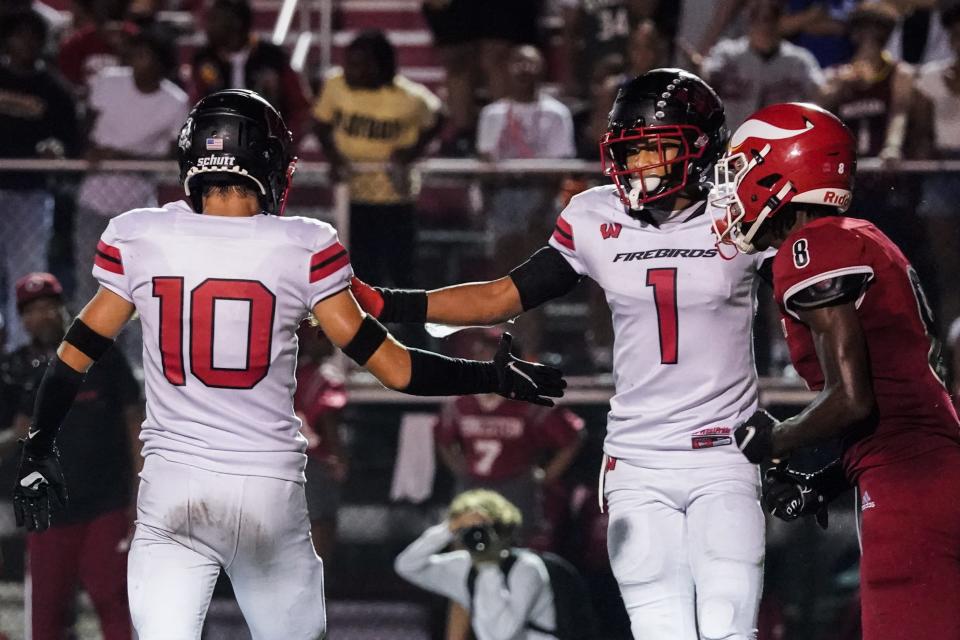 Lakota West defensive back Malik Hartford (1) celebrates with teammate Drew Minich (10) after a stop during the second half of the game with Princeton Sept. 16.