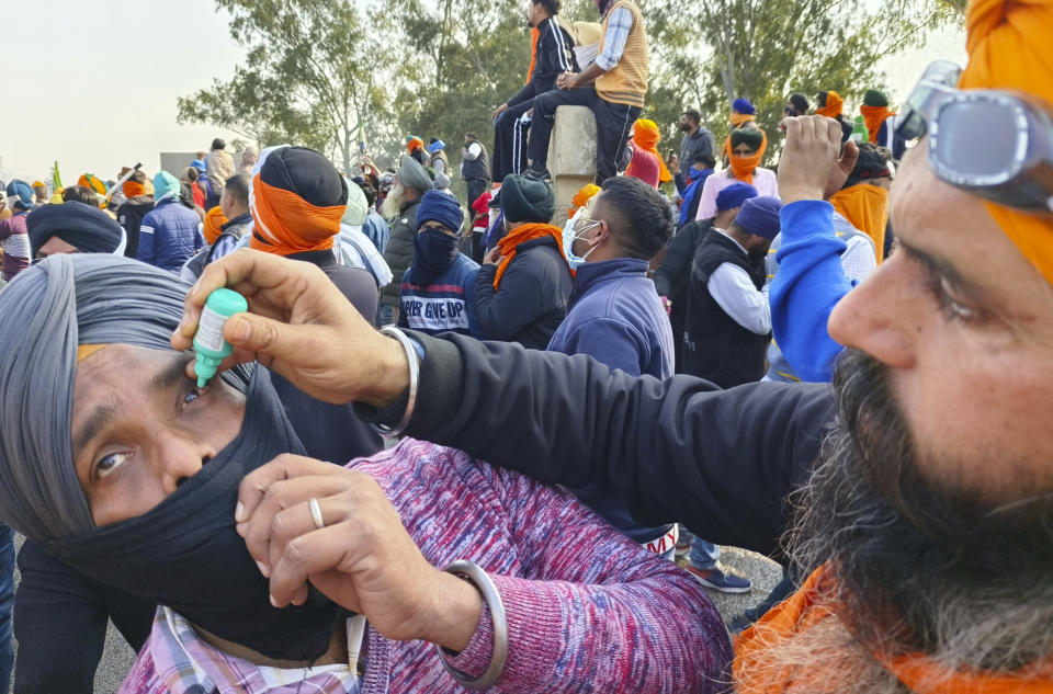 A farmer administers eye drops to a fellow protester as a precaution against tear gas near Shambhu border that divides northern Punjab and Haryana states, almost 200 km (125 miles) from New Delhi, India, Wednesday, Feb.14, 2024. Protesting Indian farmers Wednesday clashed with police for a second consecutive day as tens of thousands of them tried to march to the capital New Delhi to demand guaranteed crop prices for their produce. (AP Photo/Rajesh Sachar)