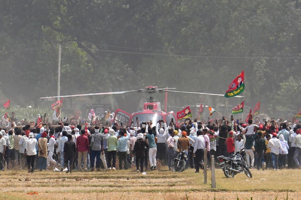 Samajwadi Party’s supporters rush towards a helicopter bringing party leader Akhilesh Yadav to an election rally in Prayagraj, Uttar Pradesh, on 19 May 2024 (AP)