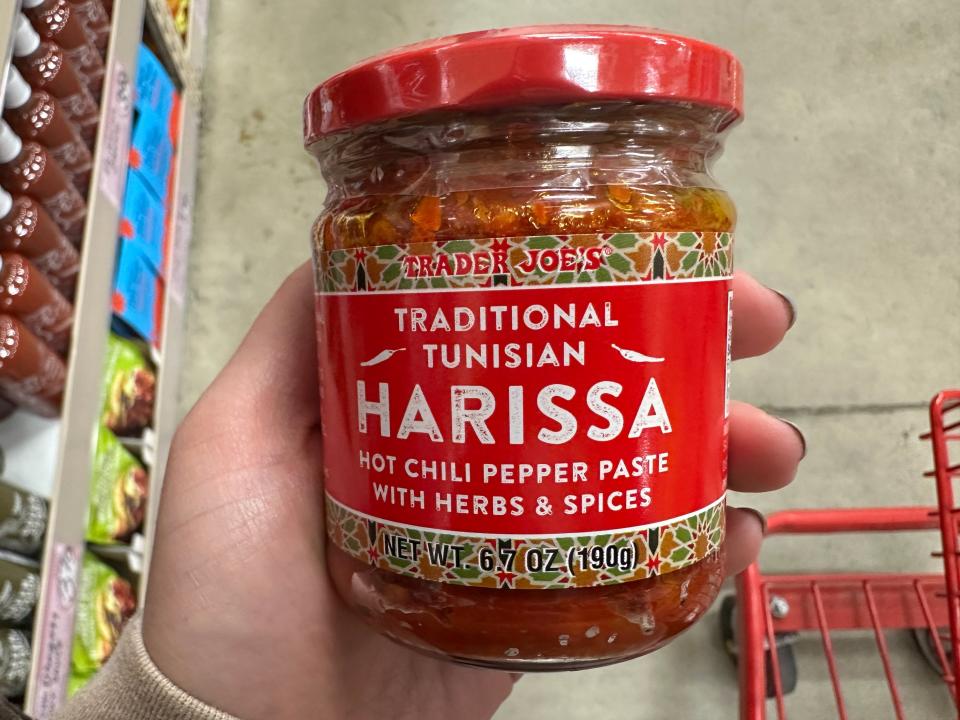 hand holding up a jar of trader joe's Tunisian harissa paste