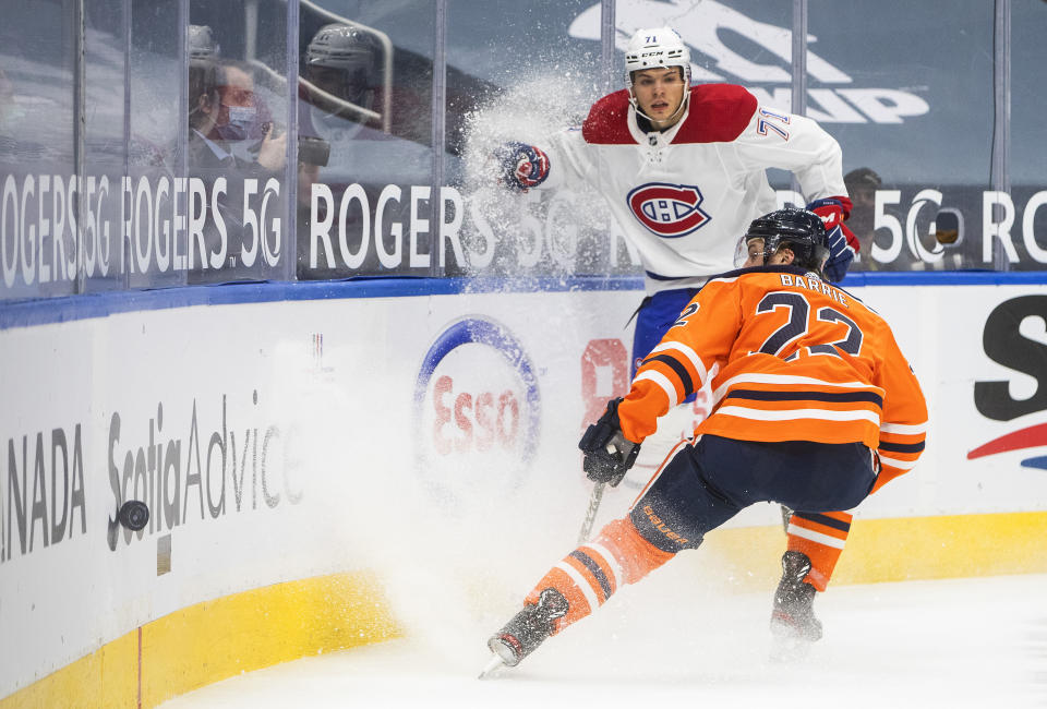 Edmonton Oilers' Tyson Barrie (22) and Montreal Canadiens' Jake Evans (71) battle for the puck during first-period NHL hockey game action in Edmonton, Alberta, Saturday, Jan. 16, 2021. (Jason Franson/The Canadian Press via AP)