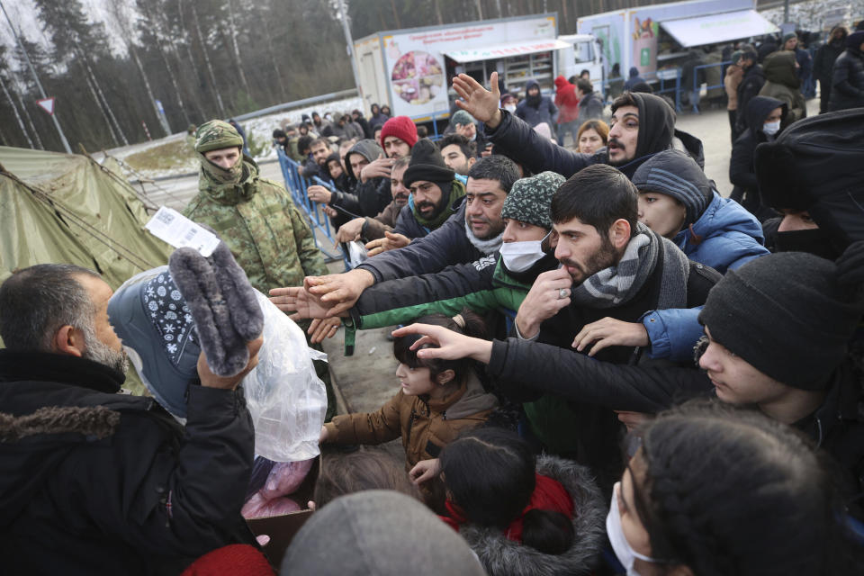 Migrants gather to get warm clothes inside a logistics center at the checkpoint "Kuznitsa" at the Belarus-Poland border near Grodno, in Grodno, Belarus, Sunday, Nov. 28, 2021. The West has accused Belarusian President Alexander Lukashenko of luring thousands of migrants to Belarus with the promise of help to get to Western Europe to use them as pawns to destabilize the 27-nation European Union in retaliation for its sanctions on his authoritarian government. Belarus denies engineering the crisis. (Leonid Shcheglov/BelTA via AP)