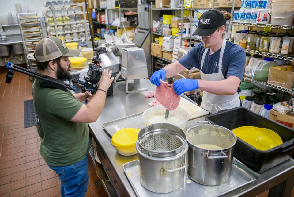 Videographer Michael Dick, left, records Busy Corner restaurant employee Brady Lenover preparing a tenderloin Wednesday, March 13, 2024 in Goodfield for an episode of the "America's Best Restaurants" web show.
(Credit: MATT DAYHOFF/JOURNAL STAR)