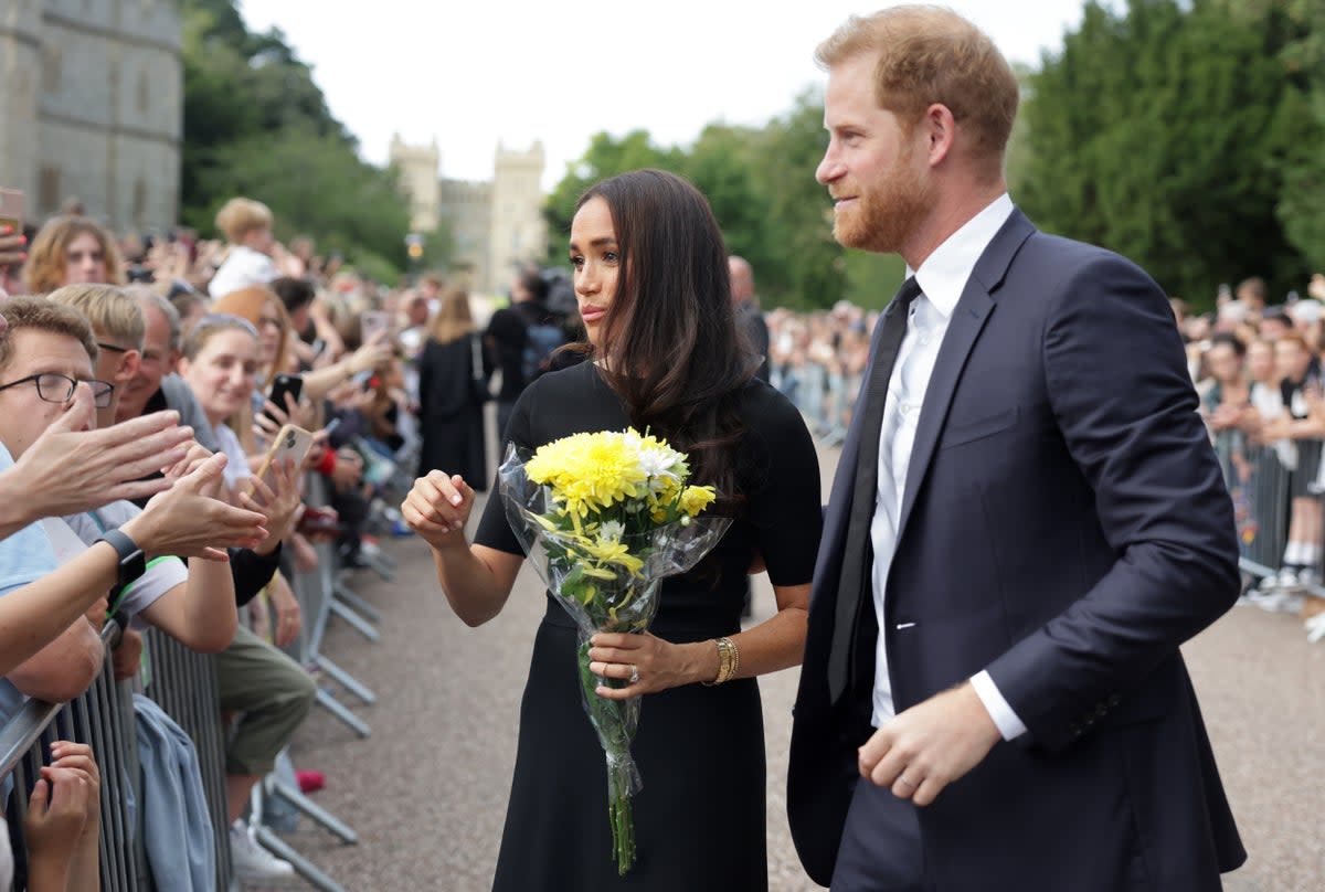 Harry y Meghan se encuentran con personas del público mientras observan las flores dejadas como tributo en el Castillo de Windsor el sábado (PA Wire)