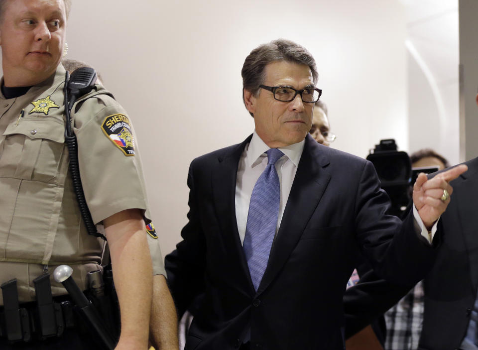 FILE - Texas Gov. Rick Perry, right, arrives at the Blackwell Thurman Criminal Justice Center for booking, in Austin, Texas, Aug. 19, 2014. Perry was facing abuse of power charges over a veto that prosecutors said he issued to settle political scores. The case against him never went to trial. (AP Photo/Eric Gay, File)